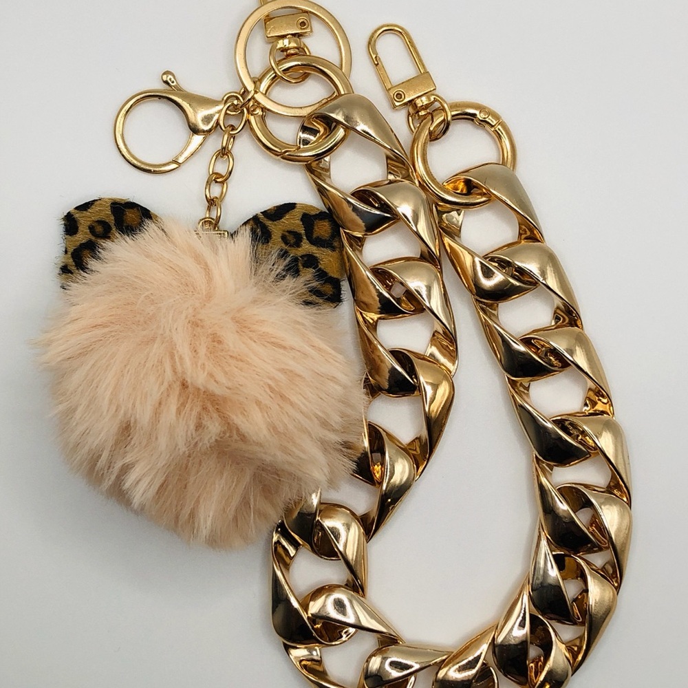 Chunky gold chain link bag strap with fuzzy beige pom pom with bow detail